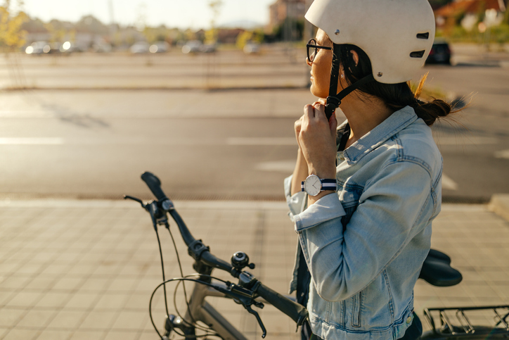 Young woman putting her helmet, preparing for the bike ride