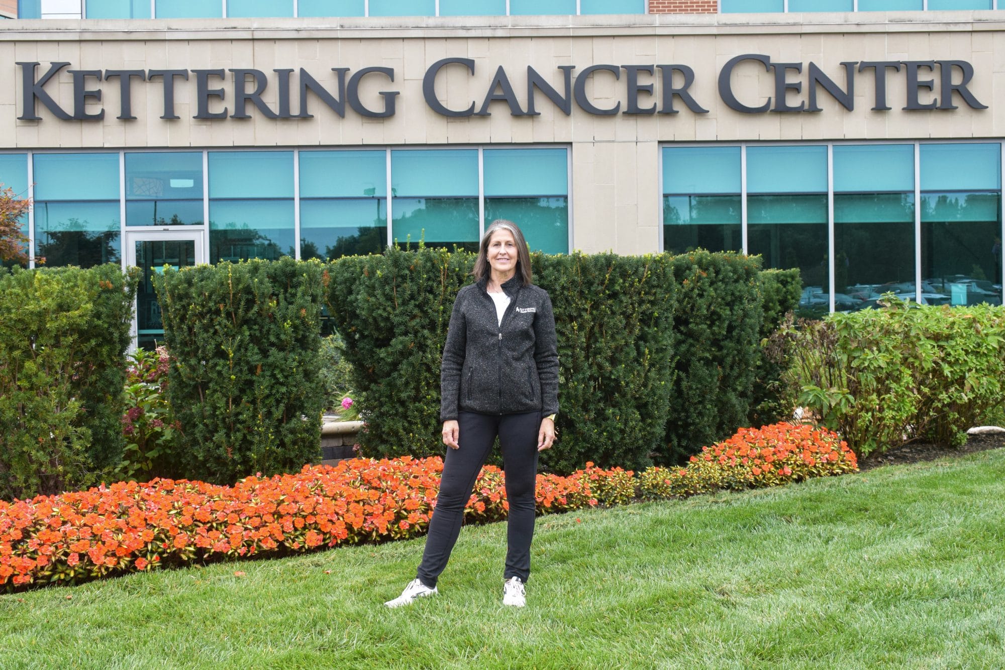 Beth stands in front of Kettering Cancer Center sign
