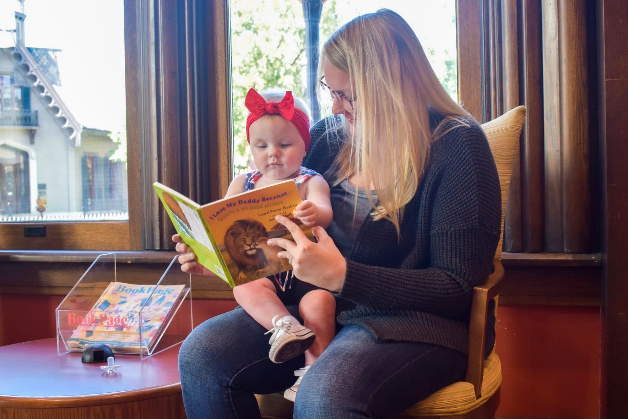 Woman participates in the Dolly Parton Imagination Library and reads a book to a baby sitting on her lap